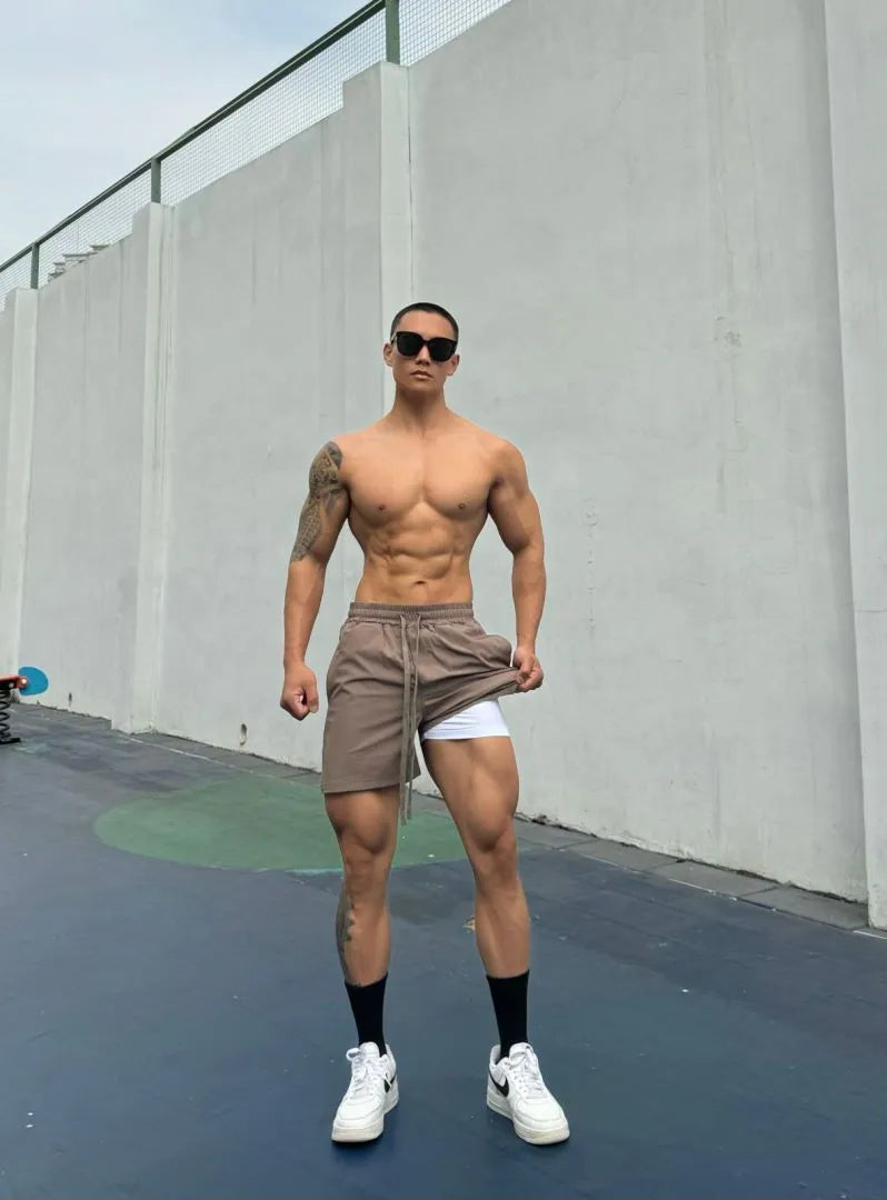 Men's black quick-drying nylon shorts with a double-layer casual design on a hanger.