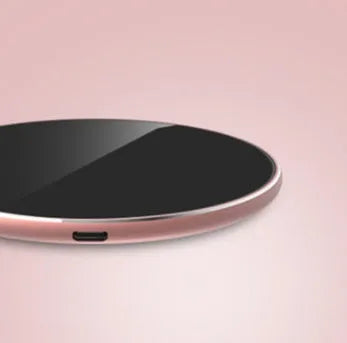 Ultra-thin aluminium wireless charging pad in rose gold colour on a wooden desk.