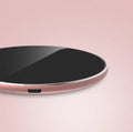 Ultra-thin aluminium wireless charging pad in rose gold colour on a wooden desk.