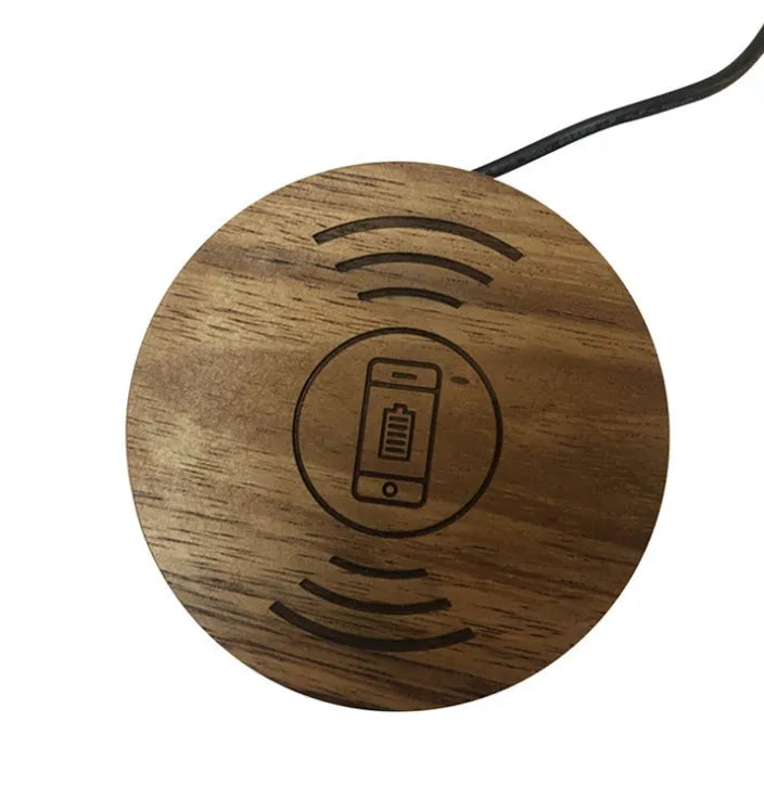Black 75mm round wireless charging disc for embedding into desks, compatible with iPhone and Samsung phones.