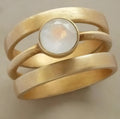 Gold-plated geometric titanium steel ring with hollow micro-inlaid white chalcedony detail.