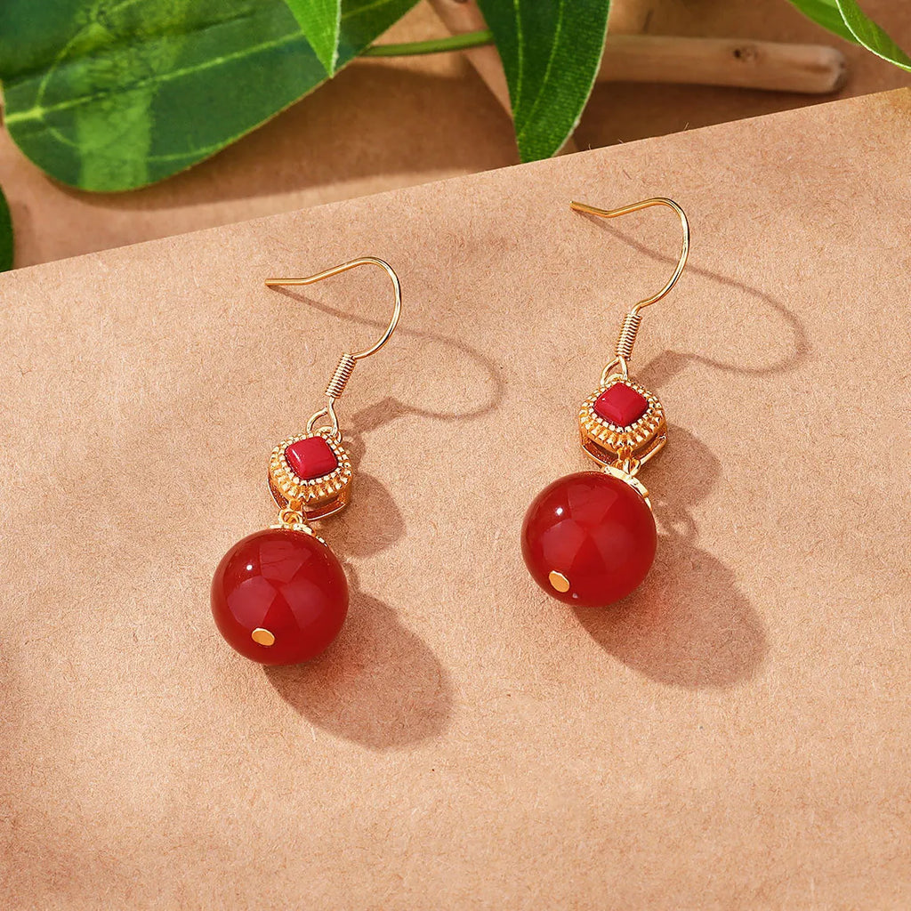 Geometric drop earrings with red agate beads, silver settings, and jasper accents on copper alloy