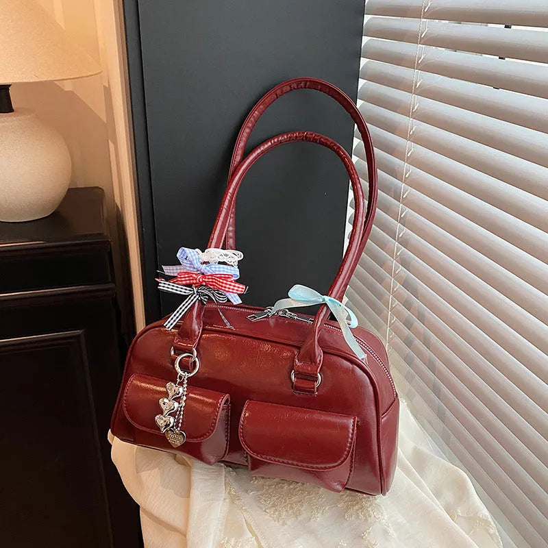 Brown retro-style women's PU leather pillow bag with flap and double strap, shown with ribbon pendant.
