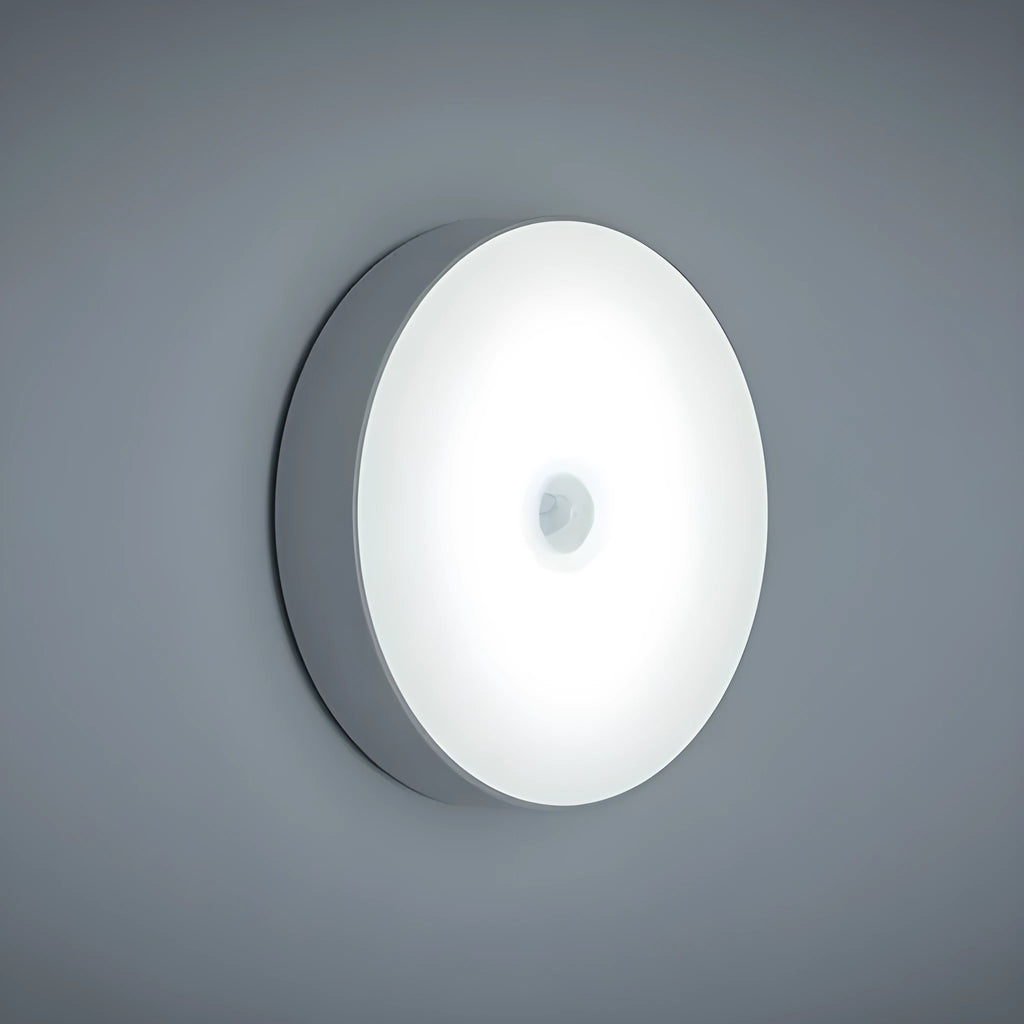 White circular motion sensor night light with USB charging port and adhesive backing