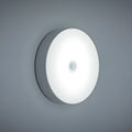 White circular motion sensor night light with USB charging port and adhesive backing