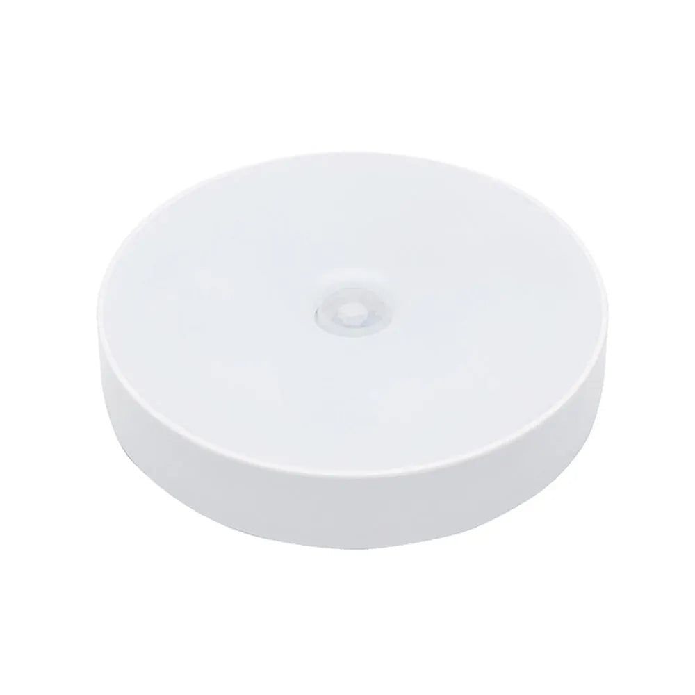 White circular motion sensor night light with USB charging port and adhesive backing