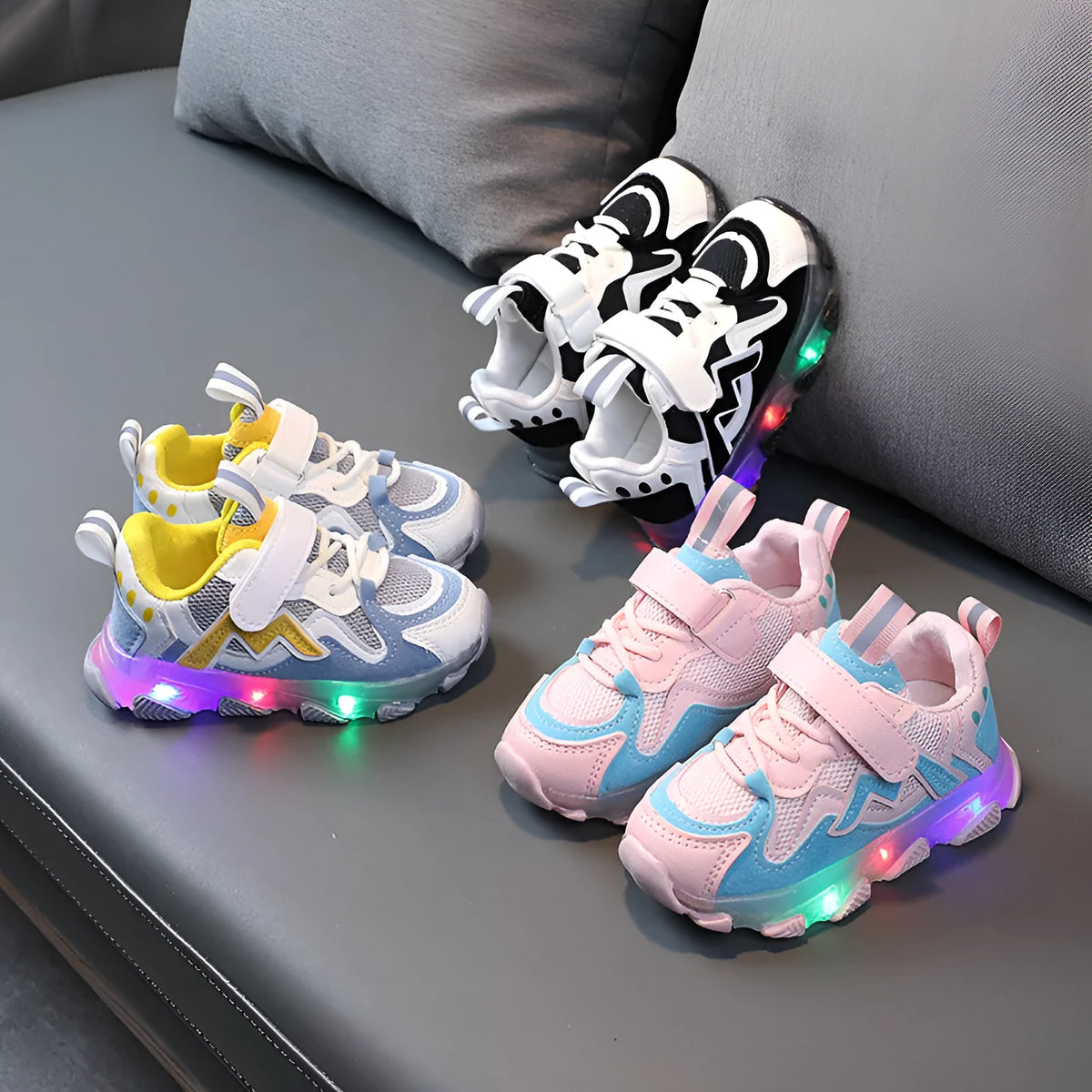 Children's bright sports sneakers with mesh panels and Velcro straps in black, pink, and grey.