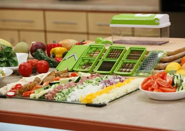 Green manual vegetable chopper with stainless steel blades and multiple cutting accessories on kitchen counter