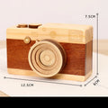Wooden camera-shaped music box on a rotating stand, packaged in a carton box.
