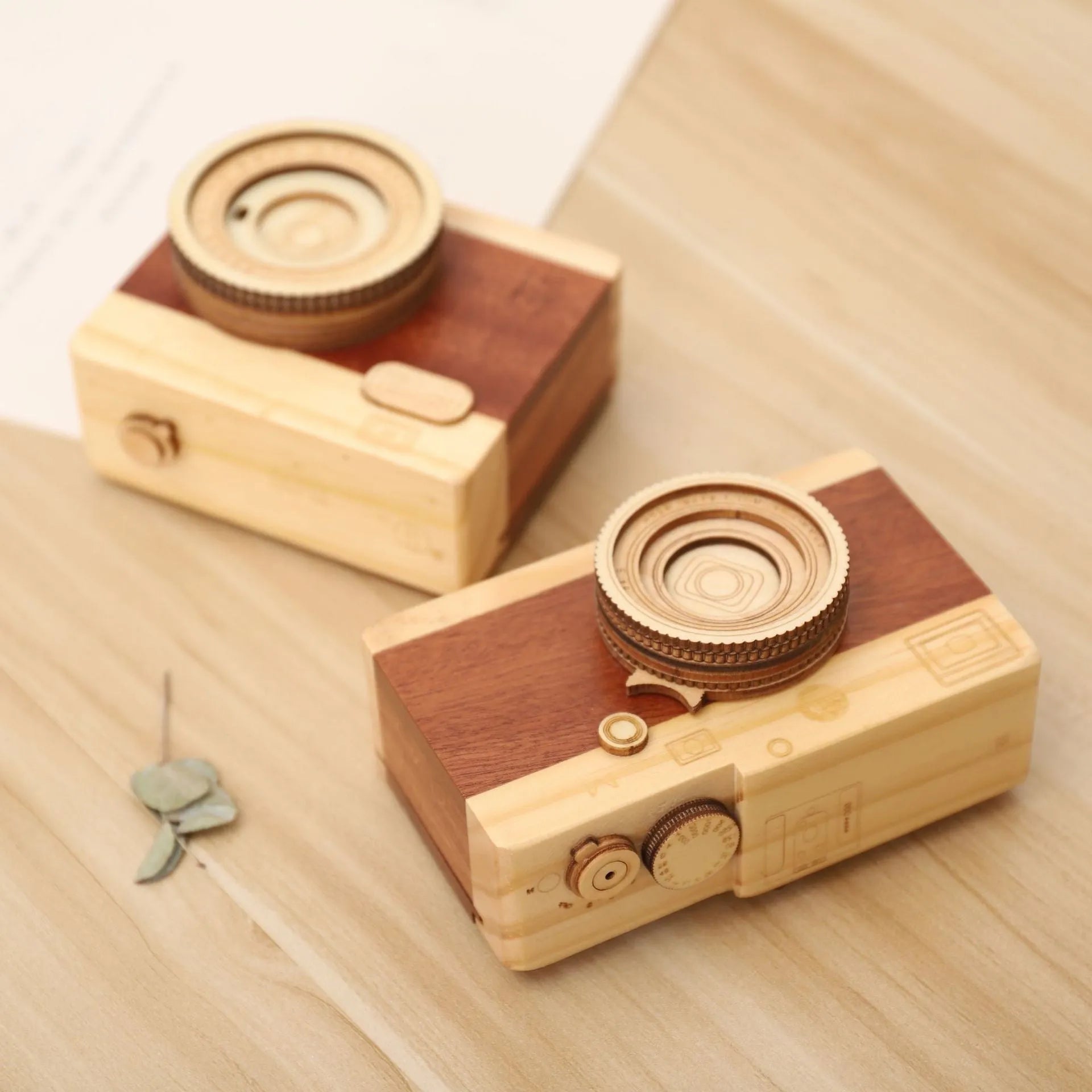 Wooden camera-shaped music box on a rotating stand, packaged in a carton box.
