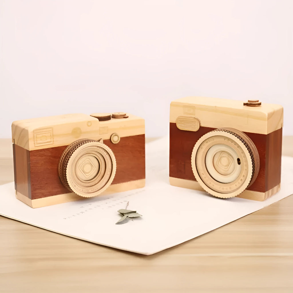 Wooden camera-shaped music box on a rotating stand, packaged in a carton box.