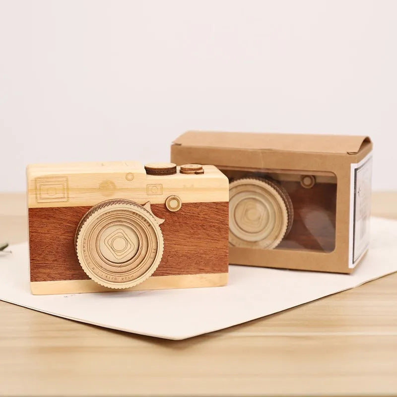 Wooden camera-shaped music box on a rotating stand, packaged in a carton box.