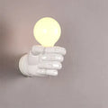 Resin wall lamp in fist design for bar or restaurant decoration in black, white, or wood grain finish.