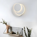 Modern round acrylic wall lamp in black or white on a bedroom wall.