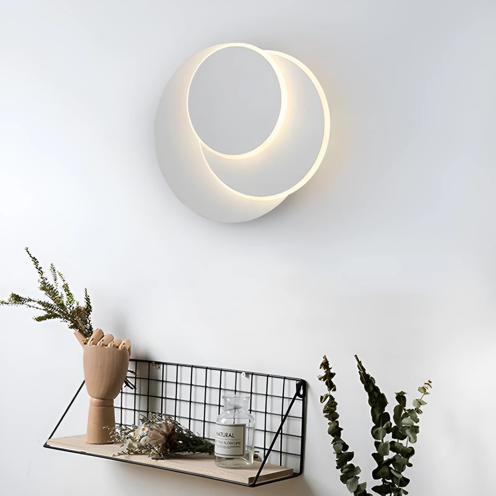 Modern round acrylic wall lamp in black or white on a bedroom wall.