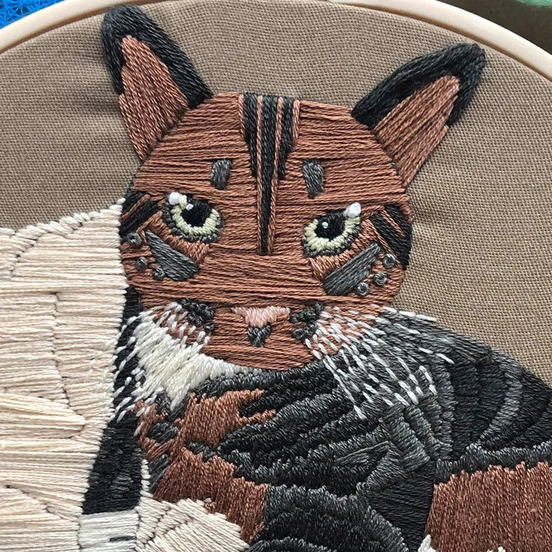 Beginners DIY cross stitch kit with cat design, embroidery threads, and fabric on a 15cm hoop.