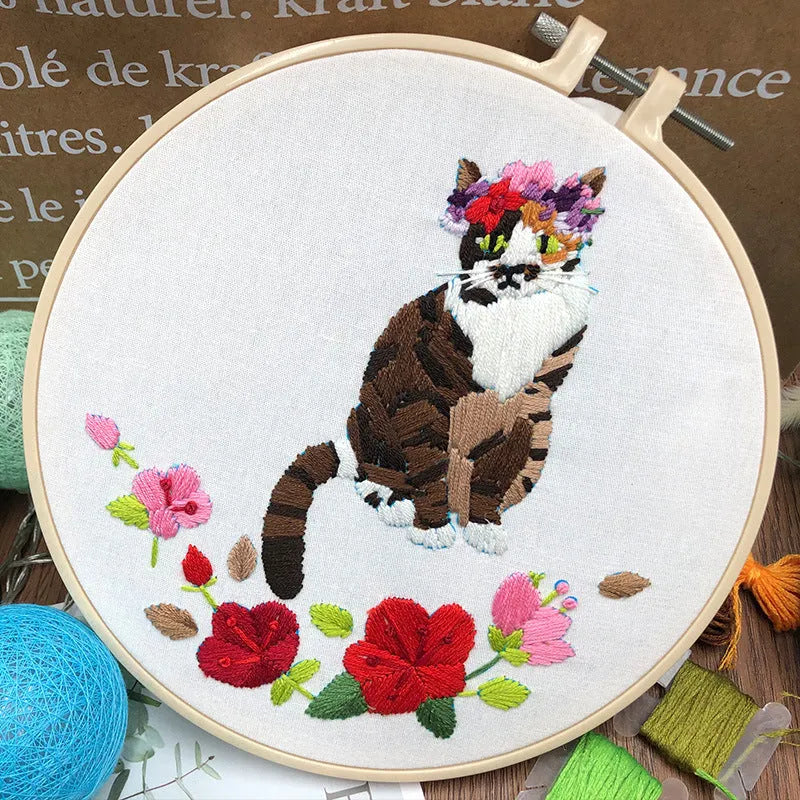 Beginners DIY cross stitch kit with cat design, embroidery threads, and fabric on a 15cm hoop.