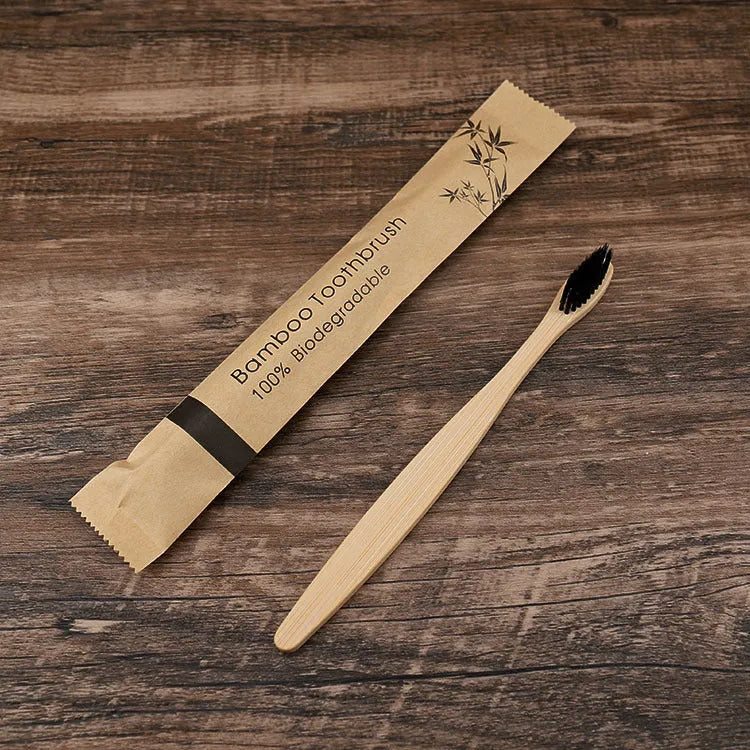 Ten bamboo toothbrushes with coloured handles and charcoal bristles laid out side by side.