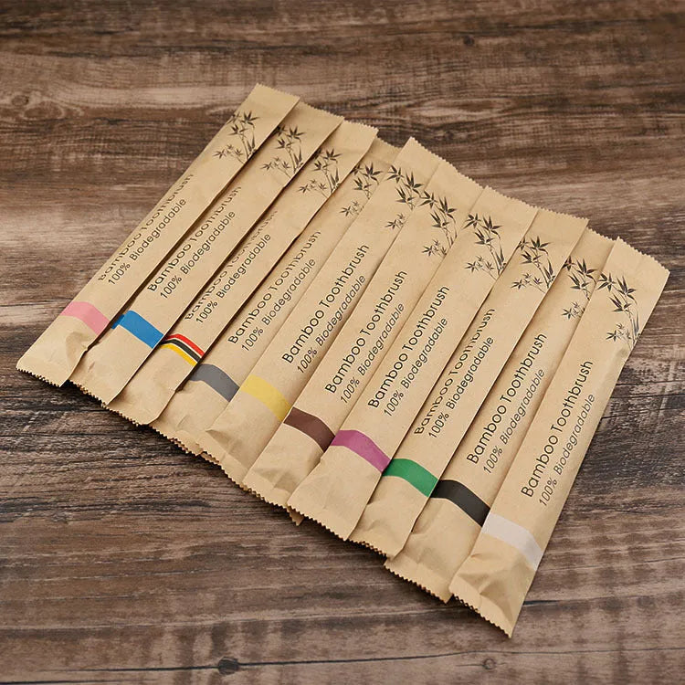Ten bamboo toothbrushes with coloured handles and charcoal bristles laid out side by side.