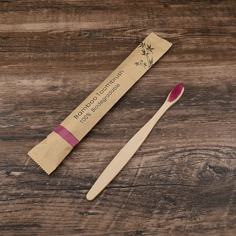 Ten bamboo toothbrushes with coloured handles and charcoal bristles laid out side by side.