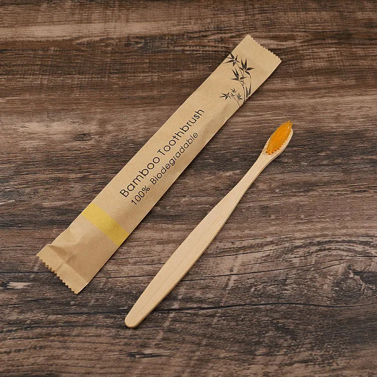 Ten bamboo toothbrushes with coloured handles and charcoal bristles laid out side by side.
