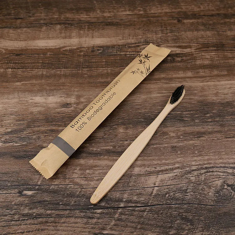 Ten bamboo toothbrushes with coloured handles and charcoal bristles laid out side by side.