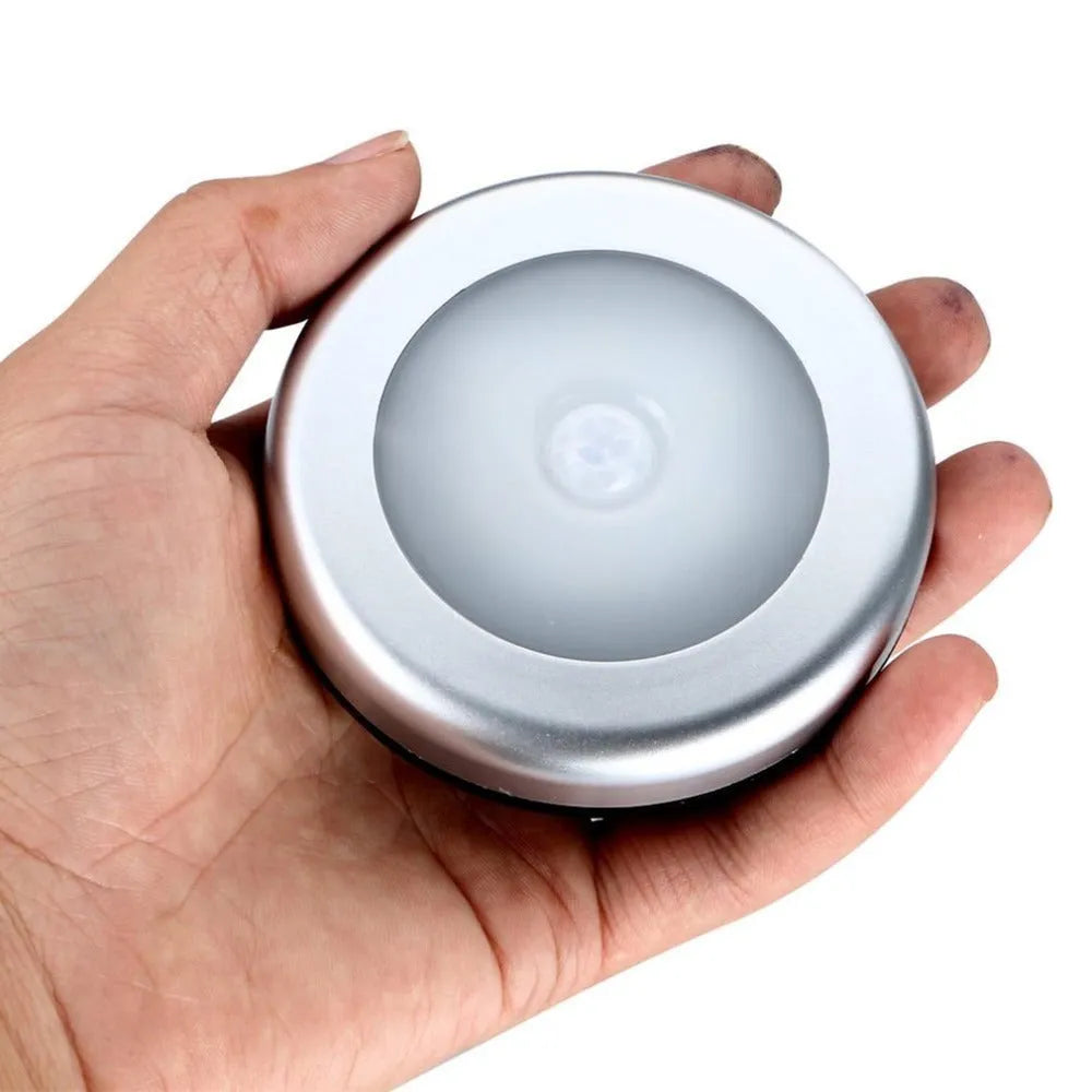 Silver-coloured circular wireless motion sensor night light on a surface
