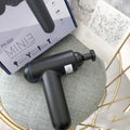 Black handheld muscle massage gun with percussion head showing USB charging port