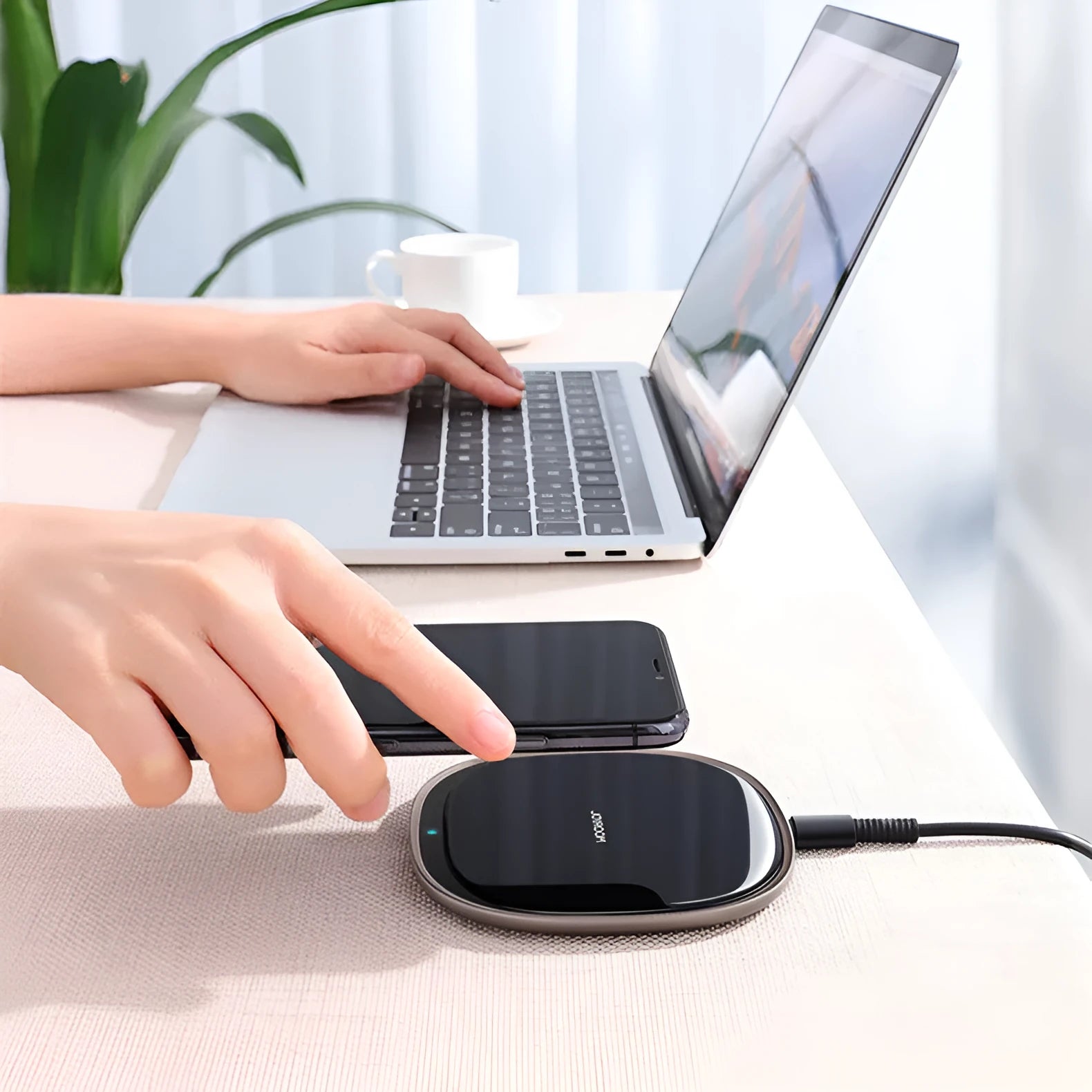 Slim black 15W Qi wireless charger with a zinc alloy frame and glass top on a wooden desk.