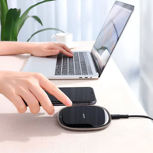 Slim black 15W Qi wireless charger with a zinc alloy frame and glass top on a wooden desk.