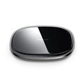 Slim black 15W Qi wireless charger with a zinc alloy frame and glass top on a wooden desk.