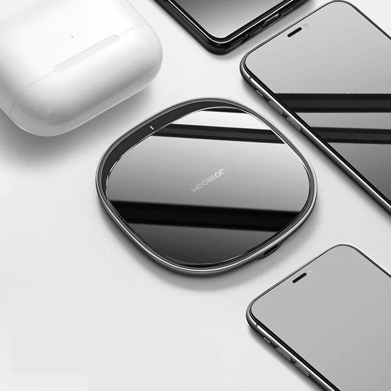 Slim black 15W Qi wireless charger with a zinc alloy frame and glass top on a wooden desk.