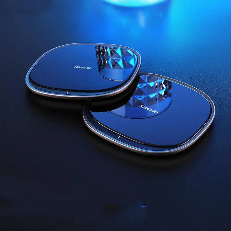 Slim black 15W Qi wireless charger with a zinc alloy frame and glass top on a wooden desk.