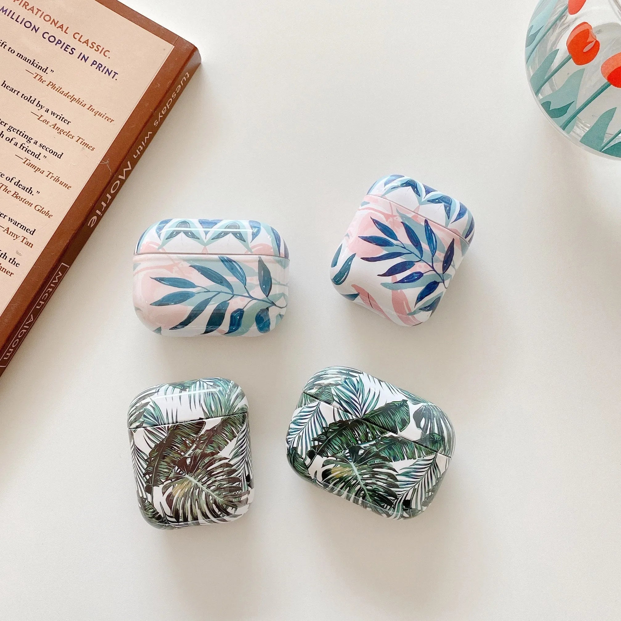 Blue and green TPU AirPods cases with banana leaf pattern for AirPods 1, 2, and Pro models.