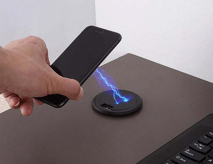 Black 75mm round wireless charging disc for embedding into desks, compatible with iPhone and Samsung phones.