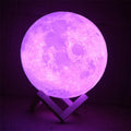3D printed white moon lamp with detailed craters on a wooden stand, glowing with soft yellow light.