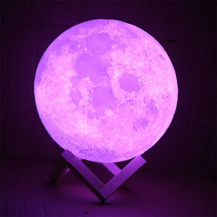 3D printed white moon lamp with detailed craters on a wooden stand, glowing with soft yellow light.