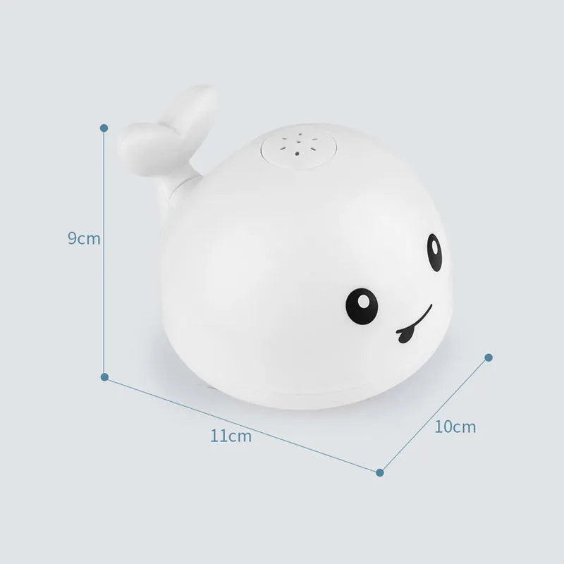 Whale-shaped electric bath toy spraying water with coloured LED lights, shown with base unit on blue background