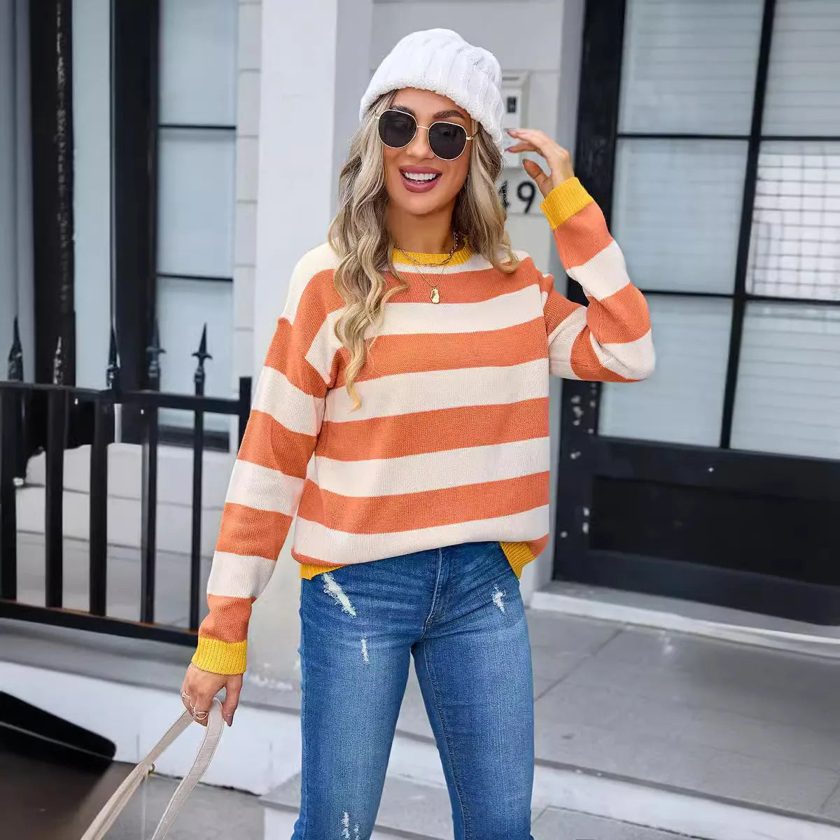 Women's loose fit long sleeve acrylic sweater in blue, showing round neck and stripe detail.