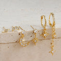 Set of six gold chain tassel drop earrings with crystal studs on a white background.