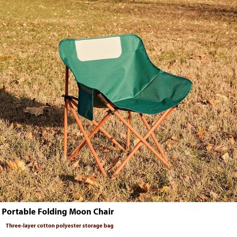 Beige folding camping chair with reclined back and steel frame on grass.