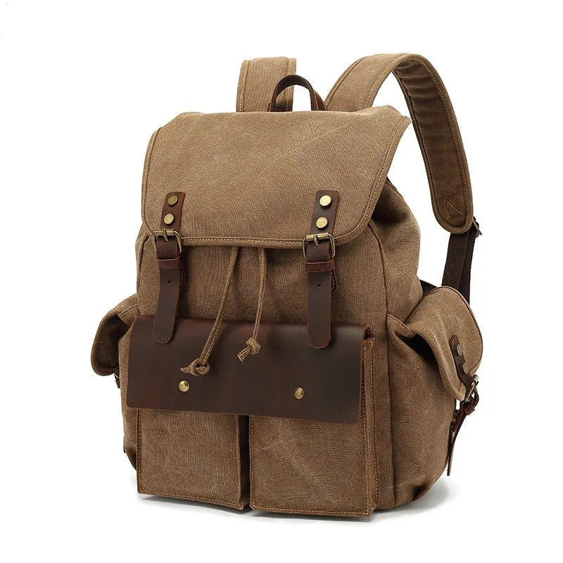 Retro canvas backpack in army green colour with antique bronze hardware, shown with a laptop to scale.