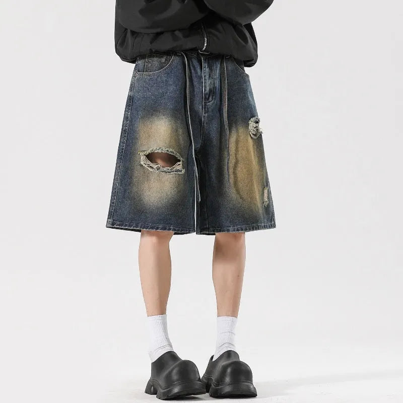 Man's loose-fit ripped jeans in retro blue denim, showing distressed detailing on legs.