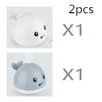 Whale-shaped electric bath toy spraying water with coloured LED lights, shown with base unit on blue background