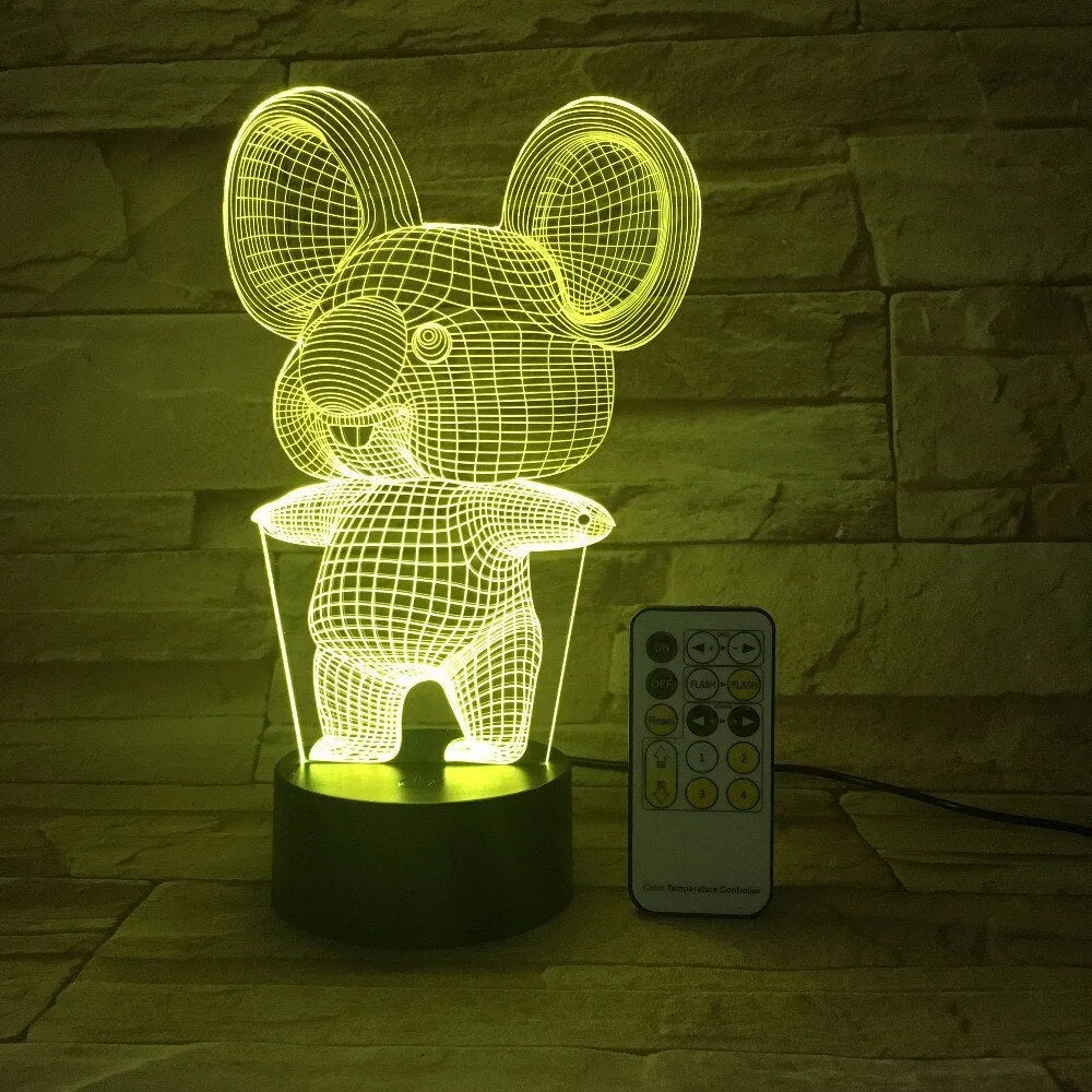 Koala-shaped LED night light with remote control on a bedside table, showing multiple colour options.