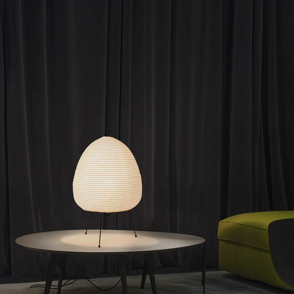 Japanese style table lamp with a white rice paper lantern shade and a silver aluminium base on a wooden table.
