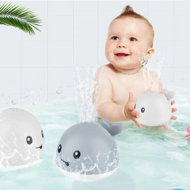 Whale-shaped electric bath toy spraying water with coloured LED lights, shown with base unit on blue background