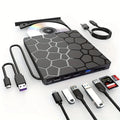 Black external USB CD drive and writer on a desk next to a laptop.