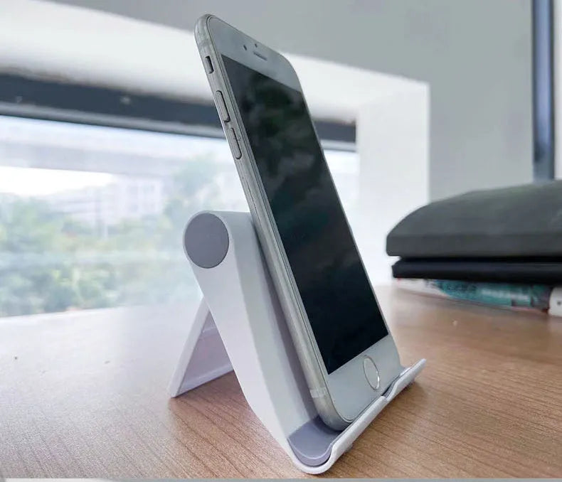 Black PE folding mobile phone and tablet stand on a wooden desktop, shown in an open, angled position.