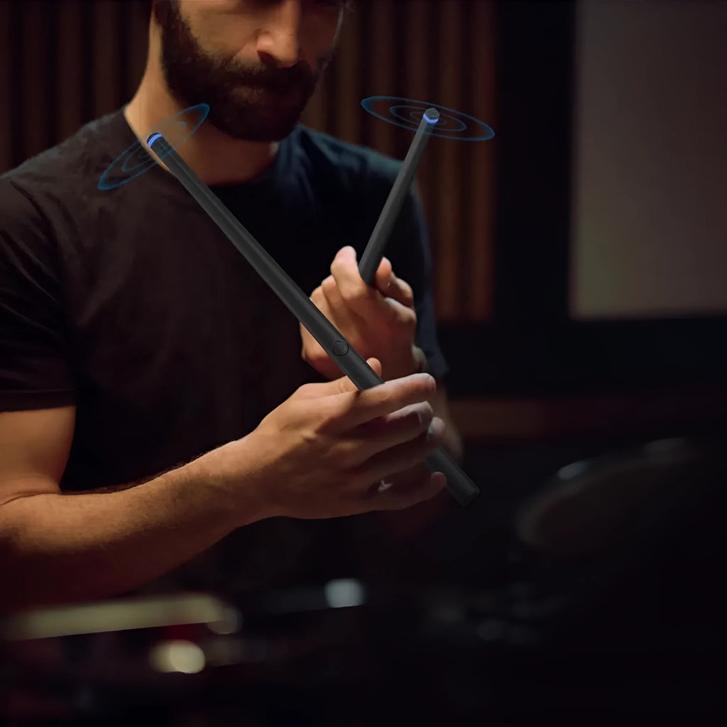 Black wireless air drum kit with drumsticks and headphones on table